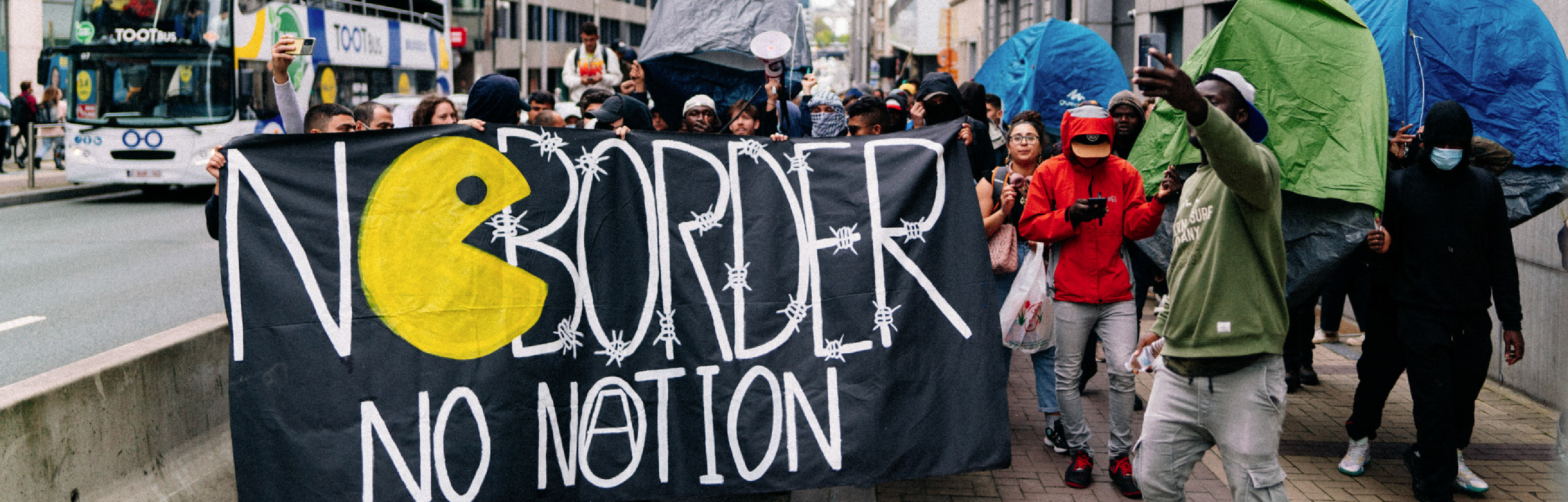 Asielzoekers en activisten die het Brusselse pand aan de Wetstraat 91 bezetten onder de naam 'Toc Toc Nicole', lopen met tentjes door de Wetstraat, om even verderop een tentenkamp neer te zetten, als protest tegen de opzettelijk gecreëerde opvangcrisis. Op het spandoek staat 'No border, no nation'