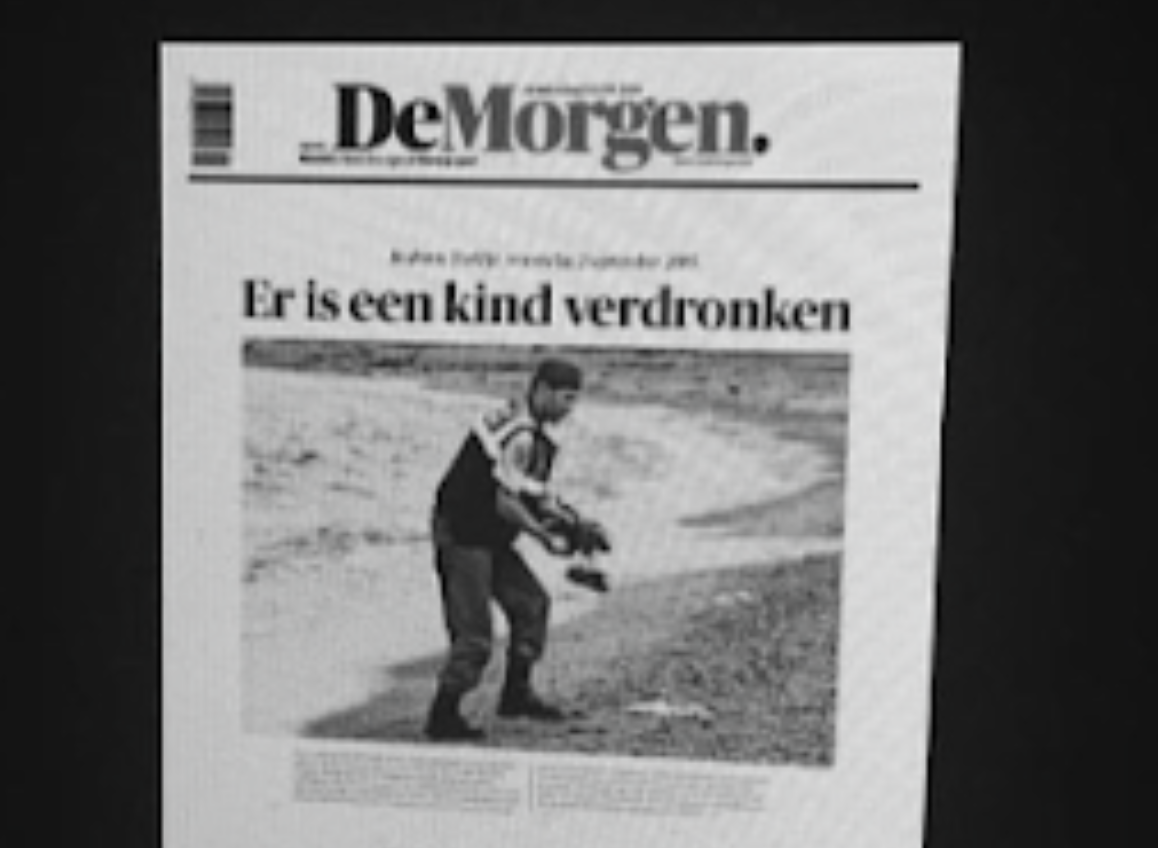 Foto van een beeldscherm met daarop de nieuwsfoto van Alan Kurdi, de jongen die wereldnieuws werd nadat hij verdronk en op het strand gefotografeerd werd.